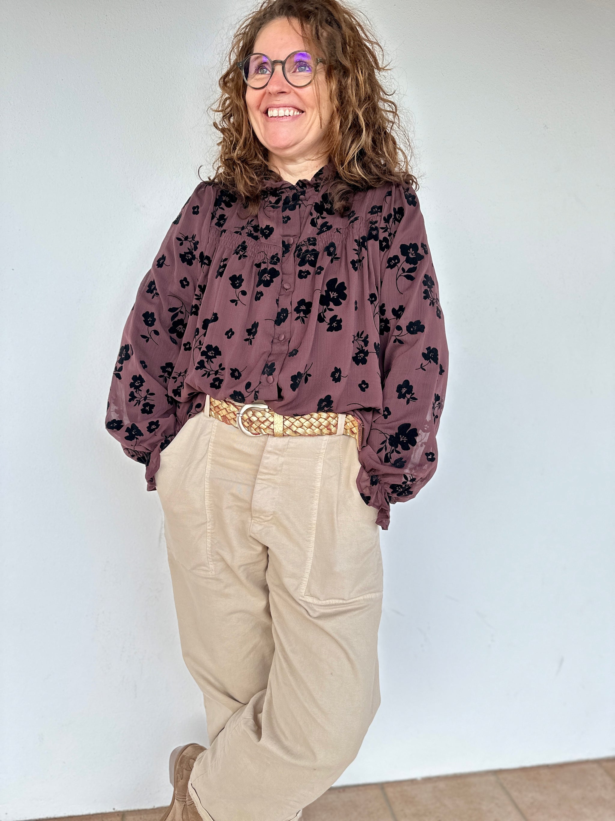 Blouse chocolat à motifs floraux noirs portée avec un pantalon clair - Abana 64480