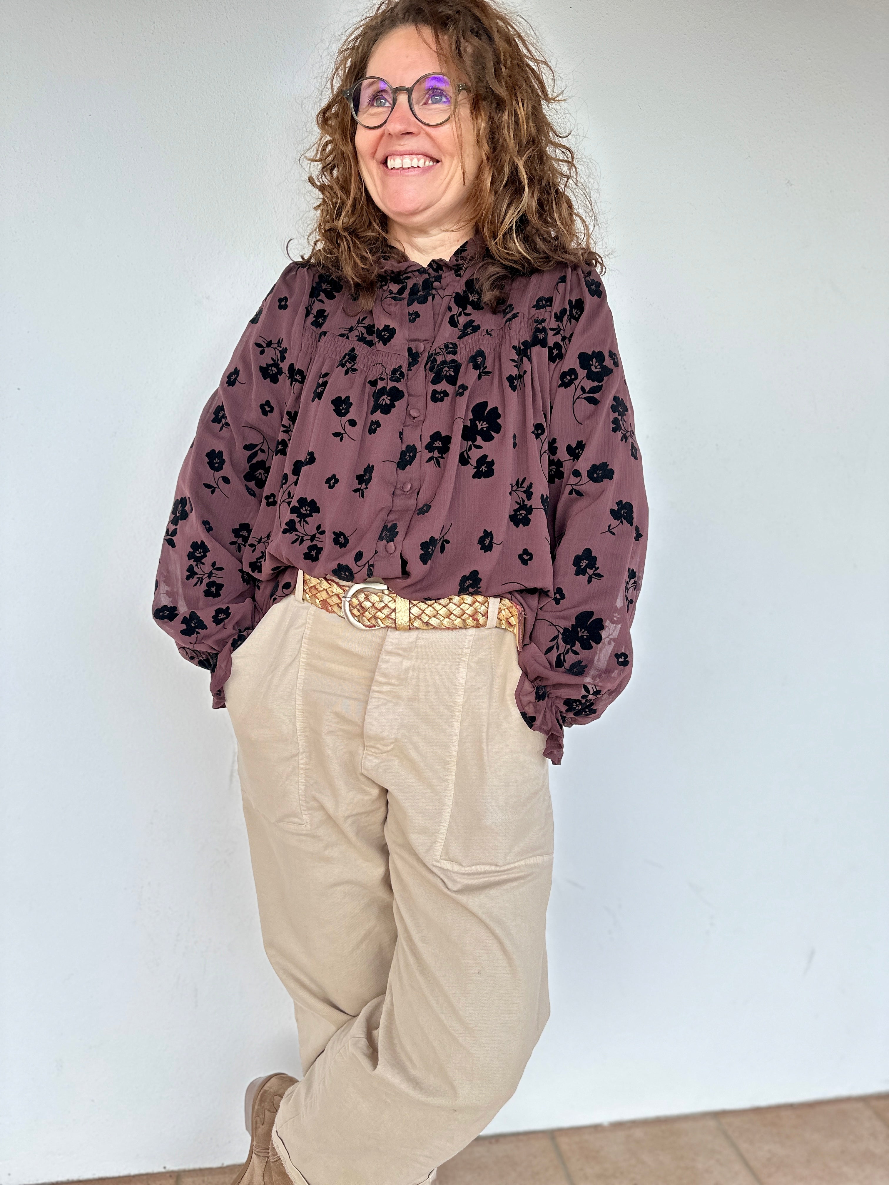 Blouse chocolat à motifs floraux noirs portée avec un pantalon clair - Abana 64480