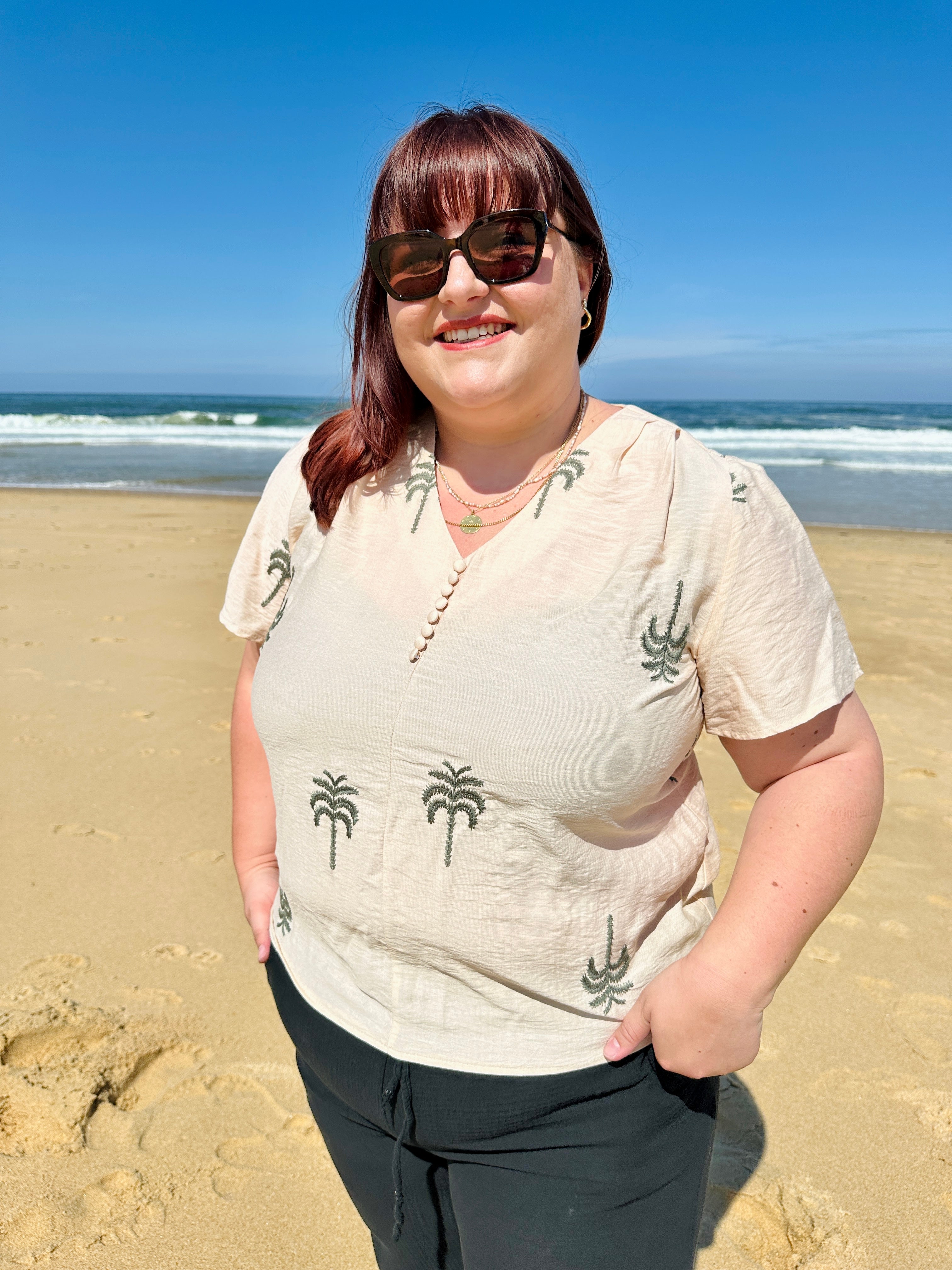 Blouse grande taille écrue à motifs palmier brodés noirs, manches courtes et col V boutonné, disponible chez Abana Boutique à Ustaritz