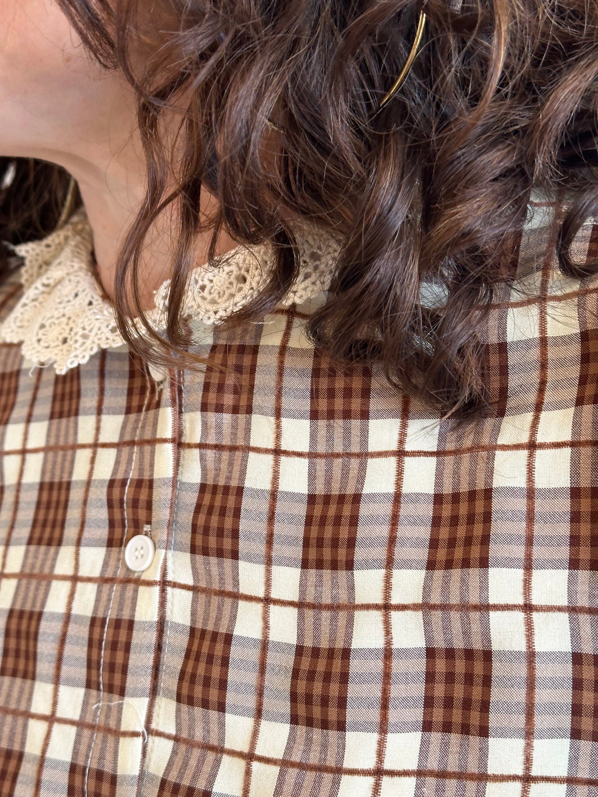 Zoom sur le col en dentelle délicate de cette chemise à carreaux, un détail raffiné qui apporte une touche féminine. À retrouver chez Abana, concept store au Pays Basque