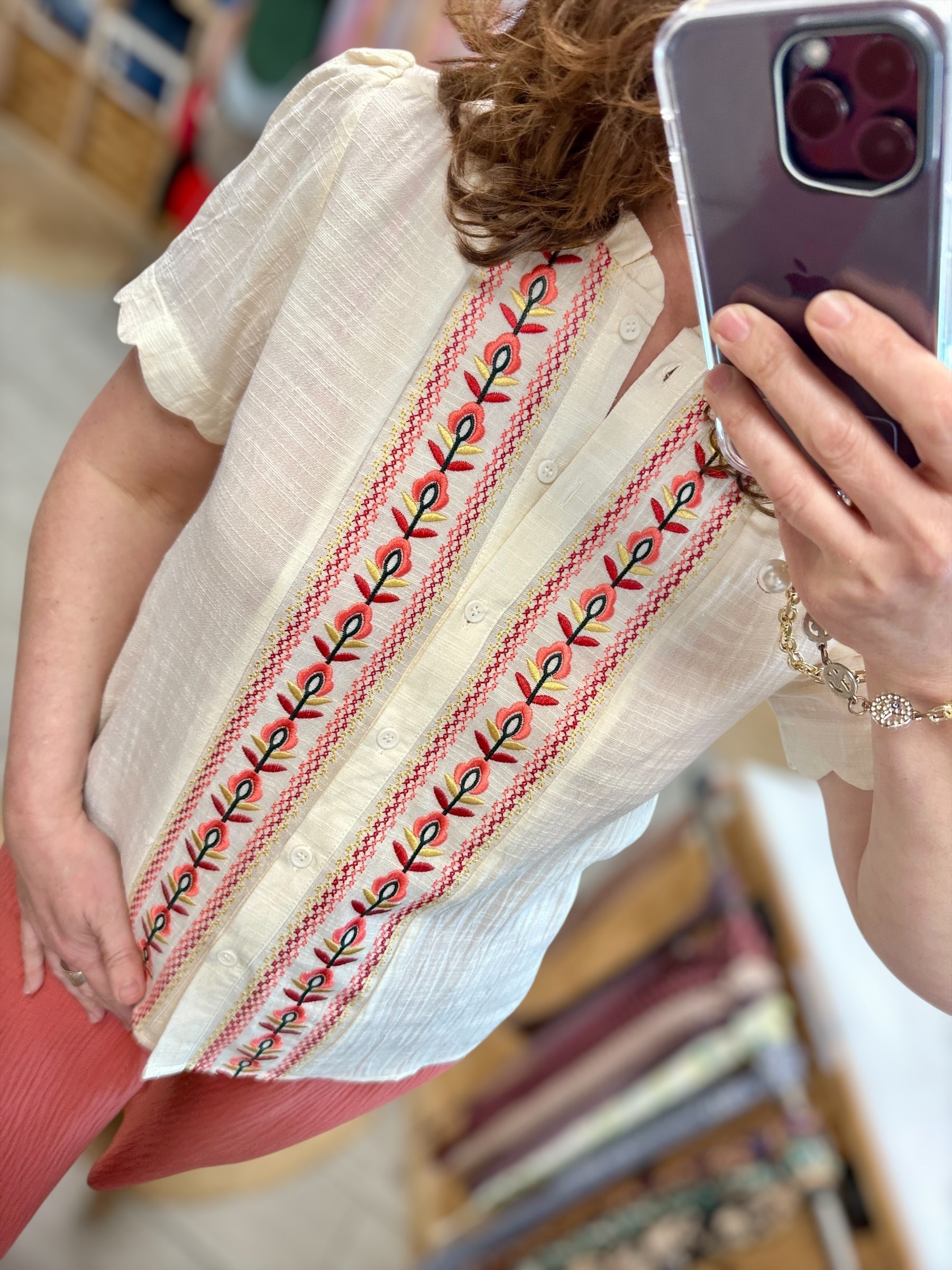 Gros plan sur les broderies rouges et vertes de la chemise écrue en coton