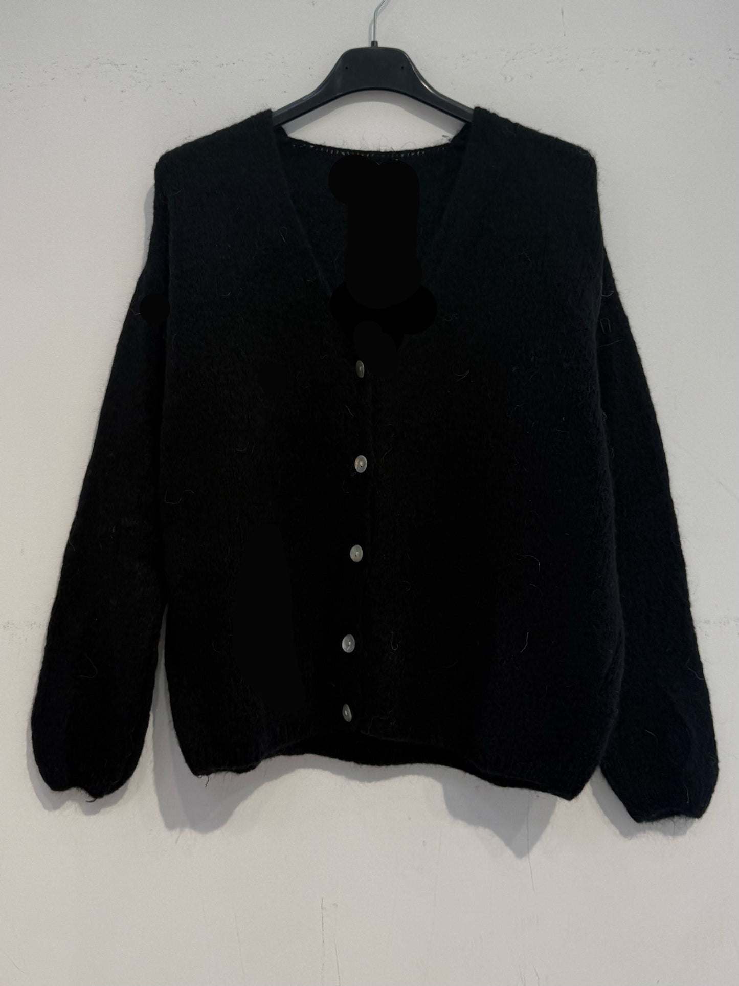 Gilet en kid mohair sur fond pastel, offrant une touche d'élégance et de confort.