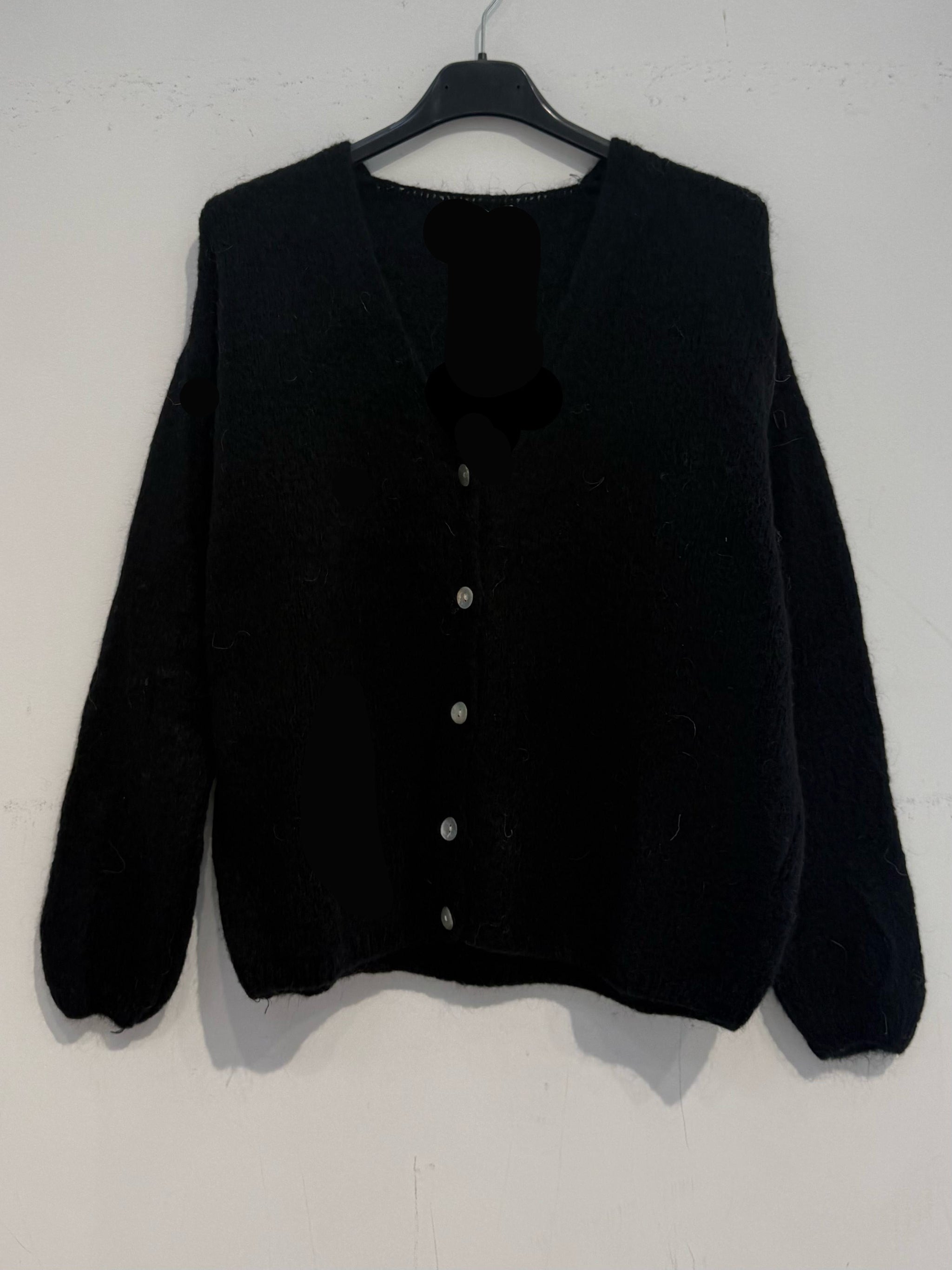 Gilet en kid mohair sur fond pastel, offrant une touche d'élégance et de confort.