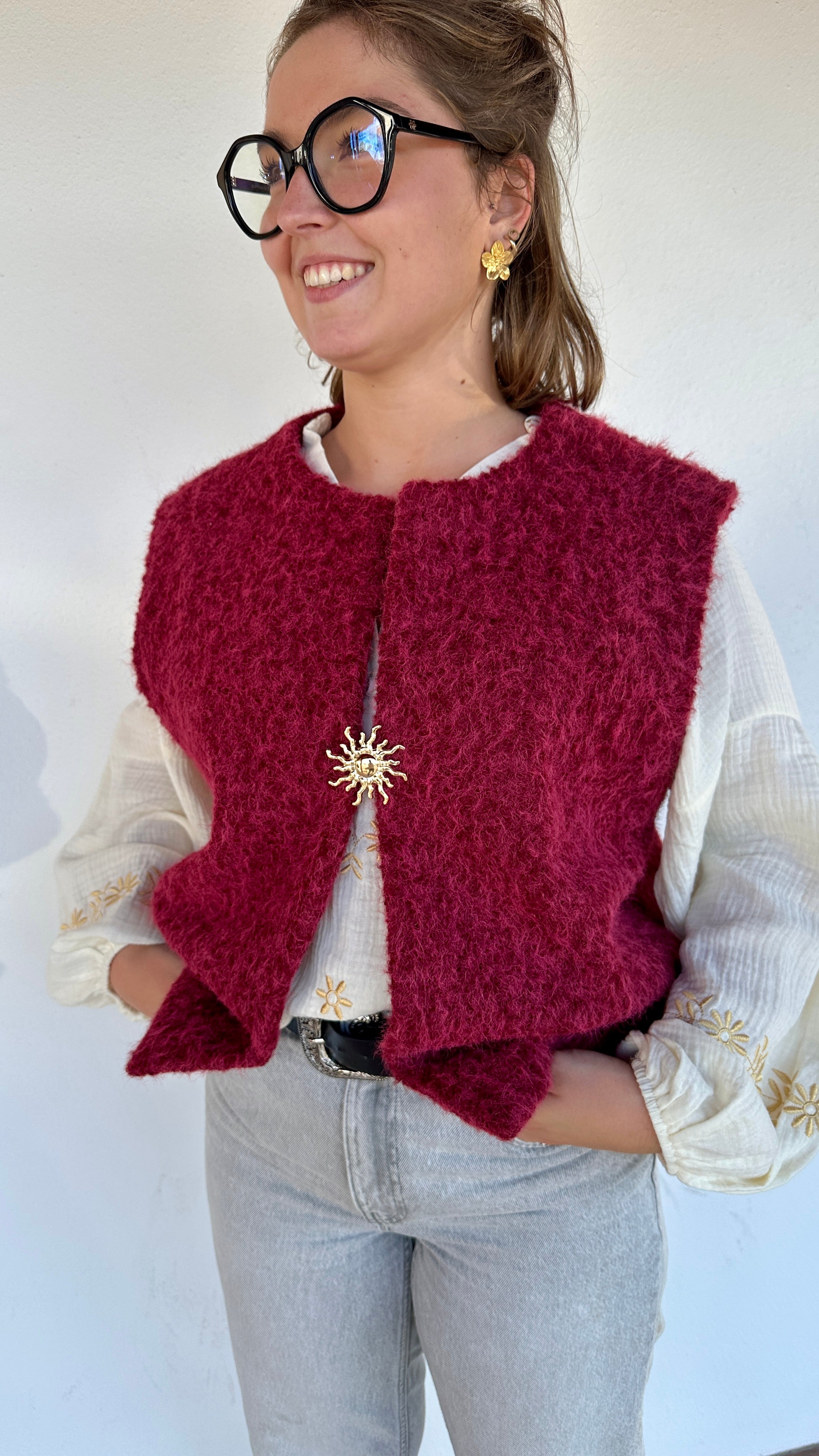 Gilet sans manches sherpa framboise avec broche dorée soleil, porté sur blouse blanche brodée– Boutique Abana 64480