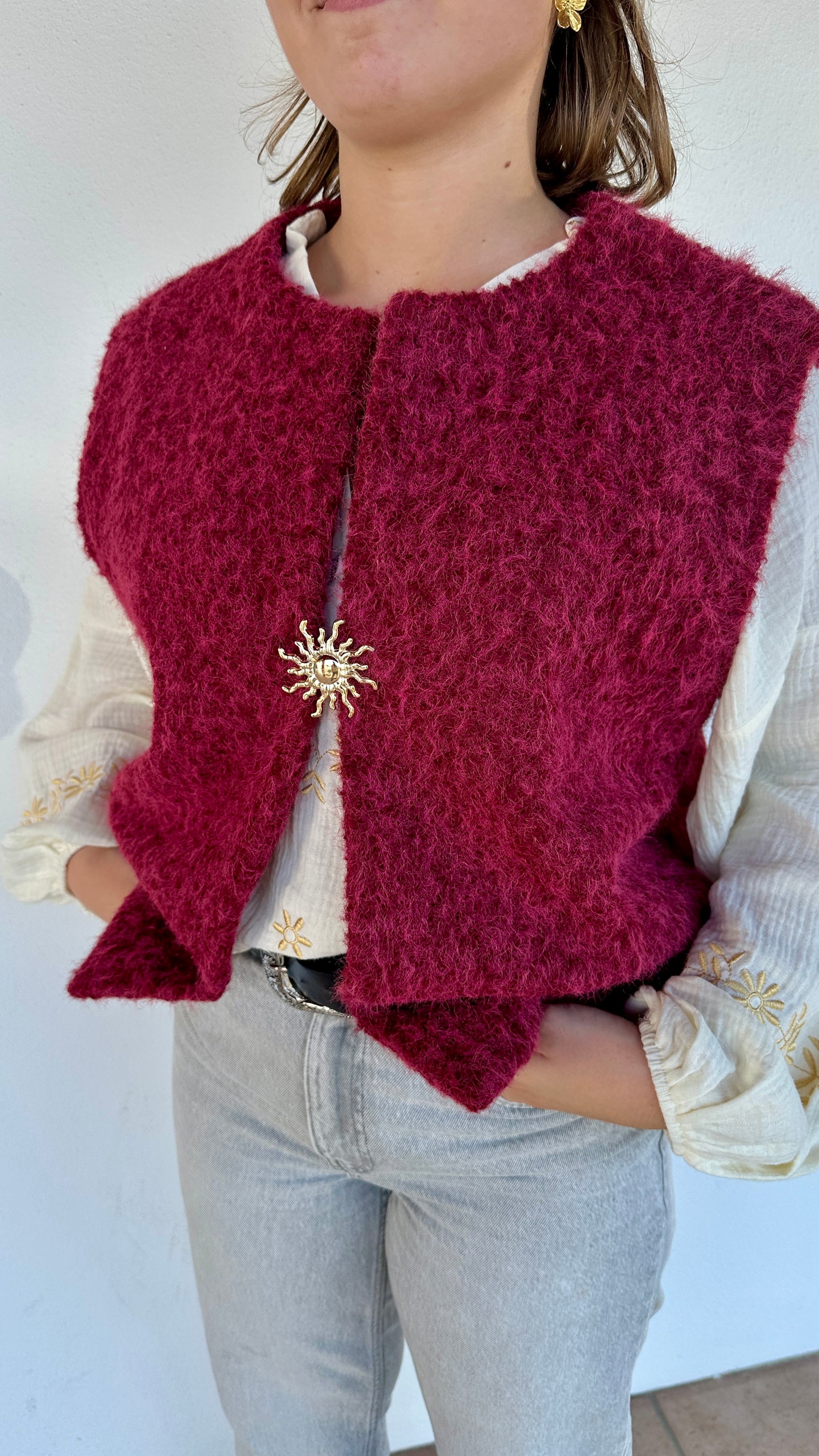 Texte alt 2 : Gilet framboise sans manches en sherpa, détail broche dorée en forme de soleil – Abana Boutique Pays Basque