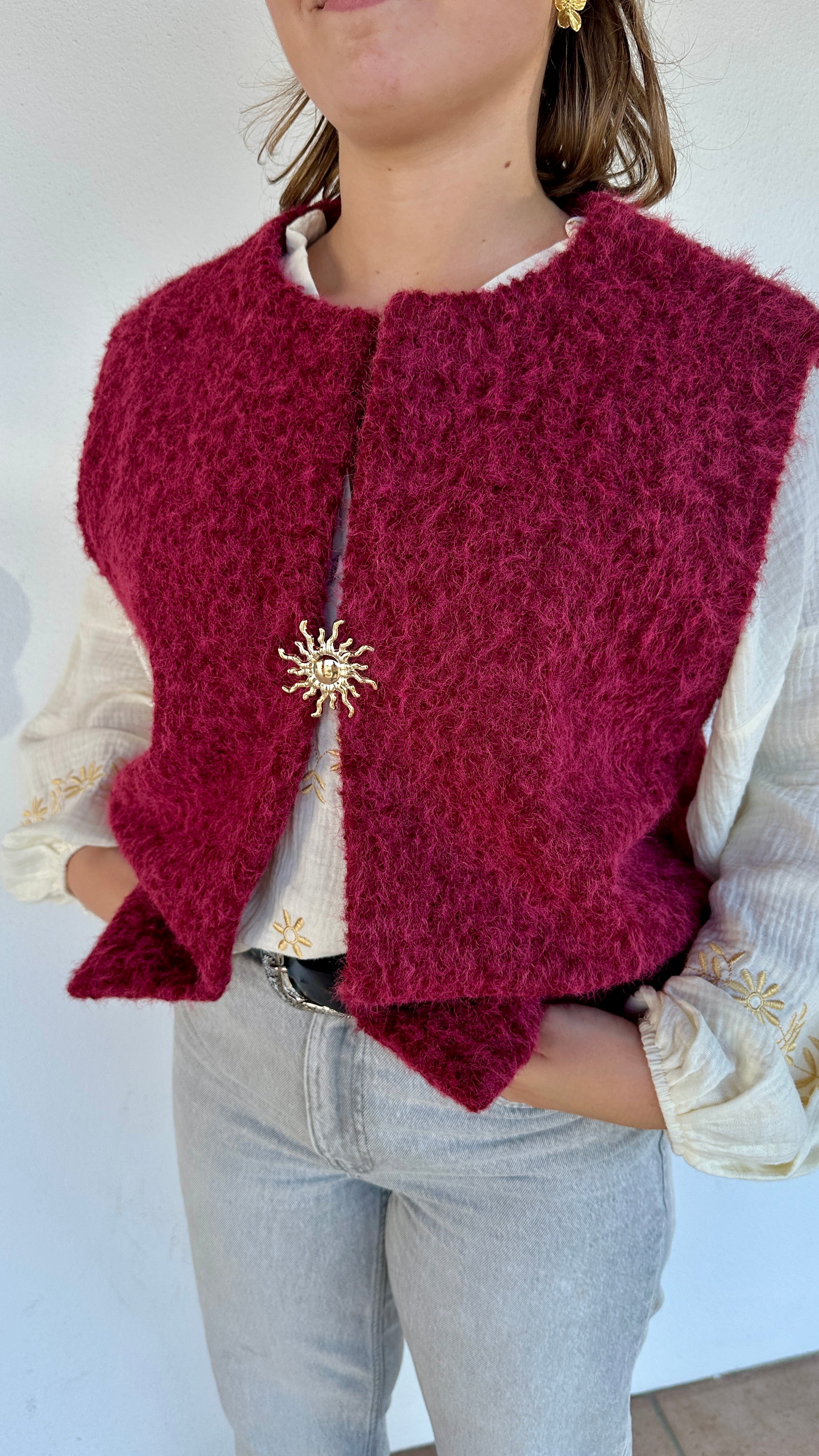 Texte alt 2 : Gilet framboise sans manches en sherpa, détail broche dorée en forme de soleil – Abana Boutique Pays Basque