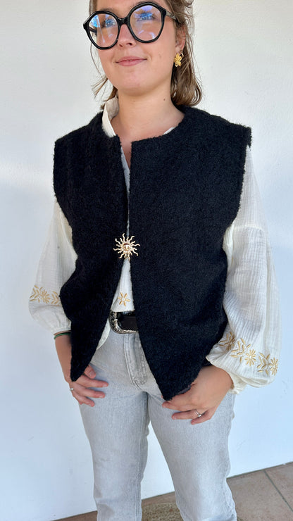 Gilet sans manches sherpa noir avec broche dorée, porté sur blouse blanche et jean clair - Abana Boutique 64310