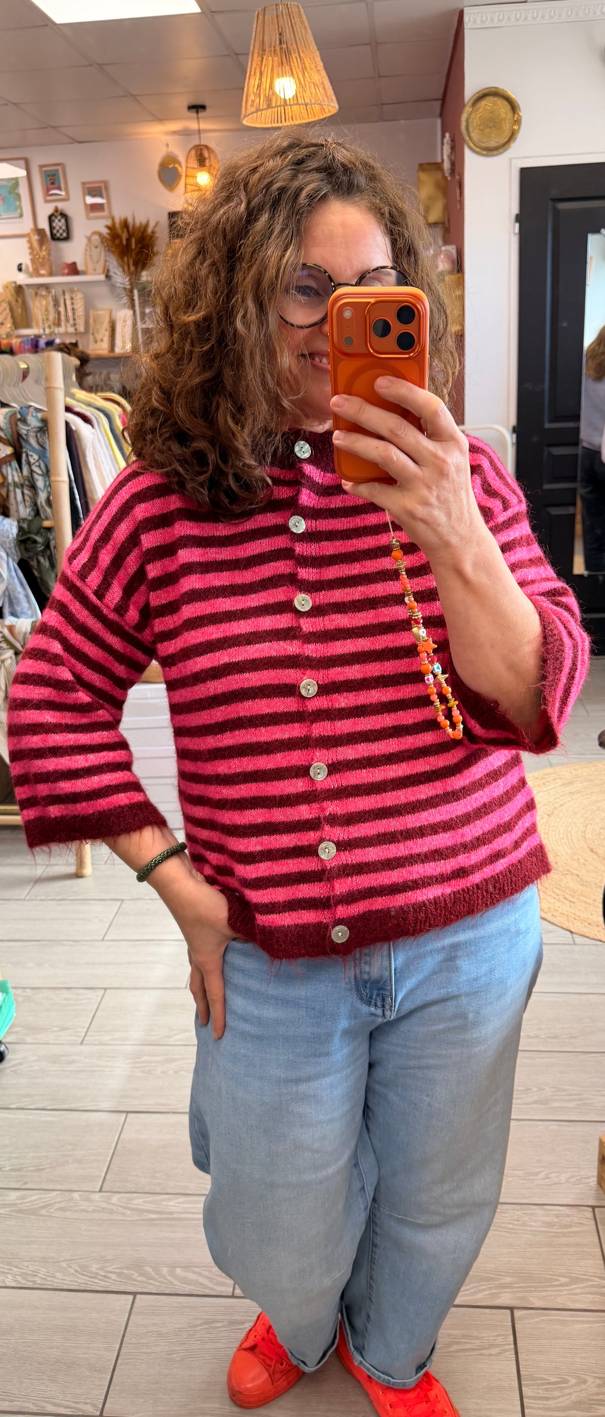 Gilet femme à rayures roses et bordeaux, boutonné sur le devant et porté avec un jean clair.