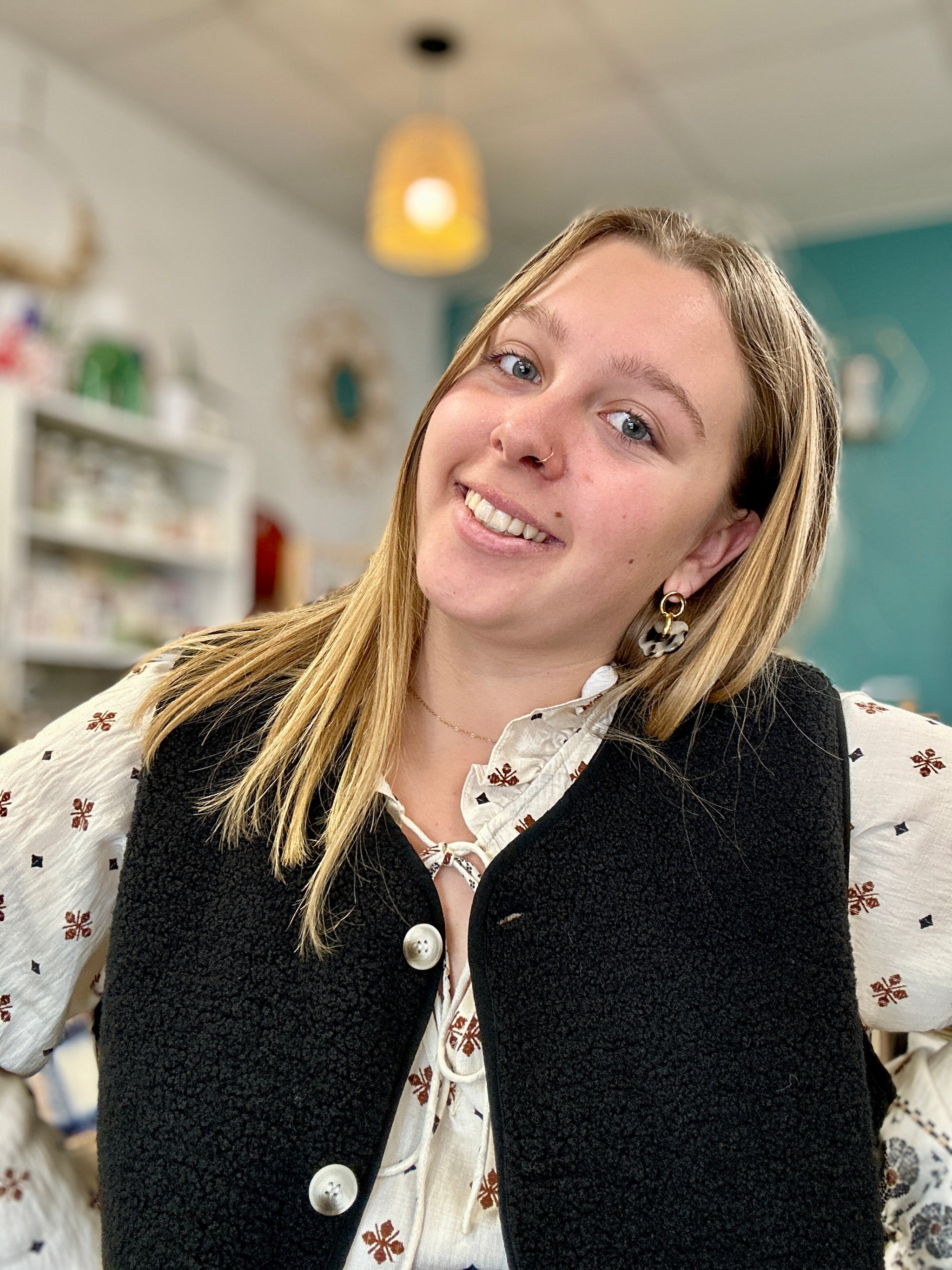 Gilet sans manches noir en moumoute porté sur une blouse blanche à motifs, parfait pour l’hiver - Abana 64480