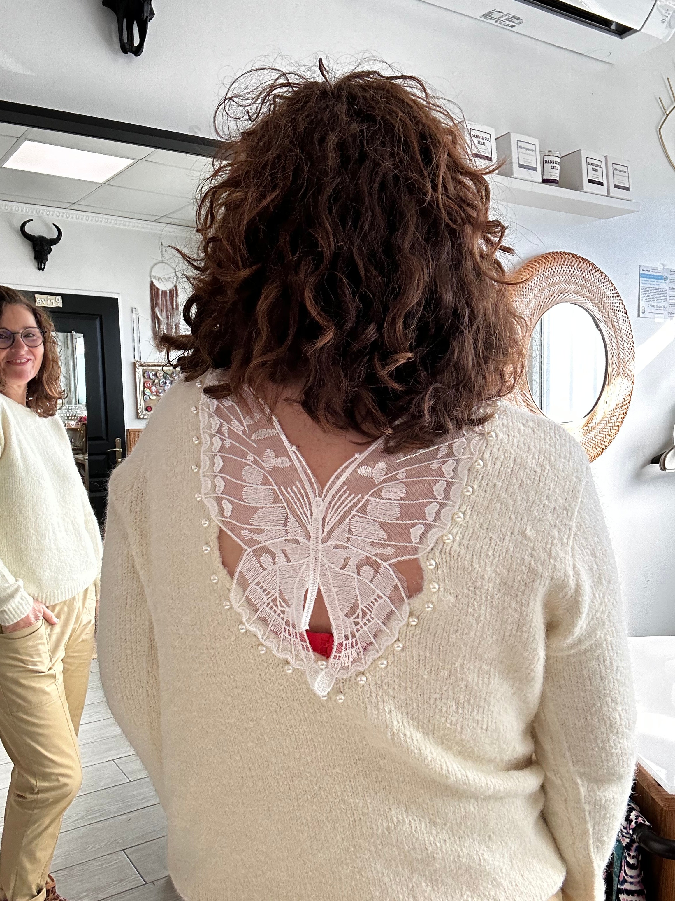 Pull écru avec détail papillon en dentelle et perles dans le dos, porté sur mannequin vu de dos.