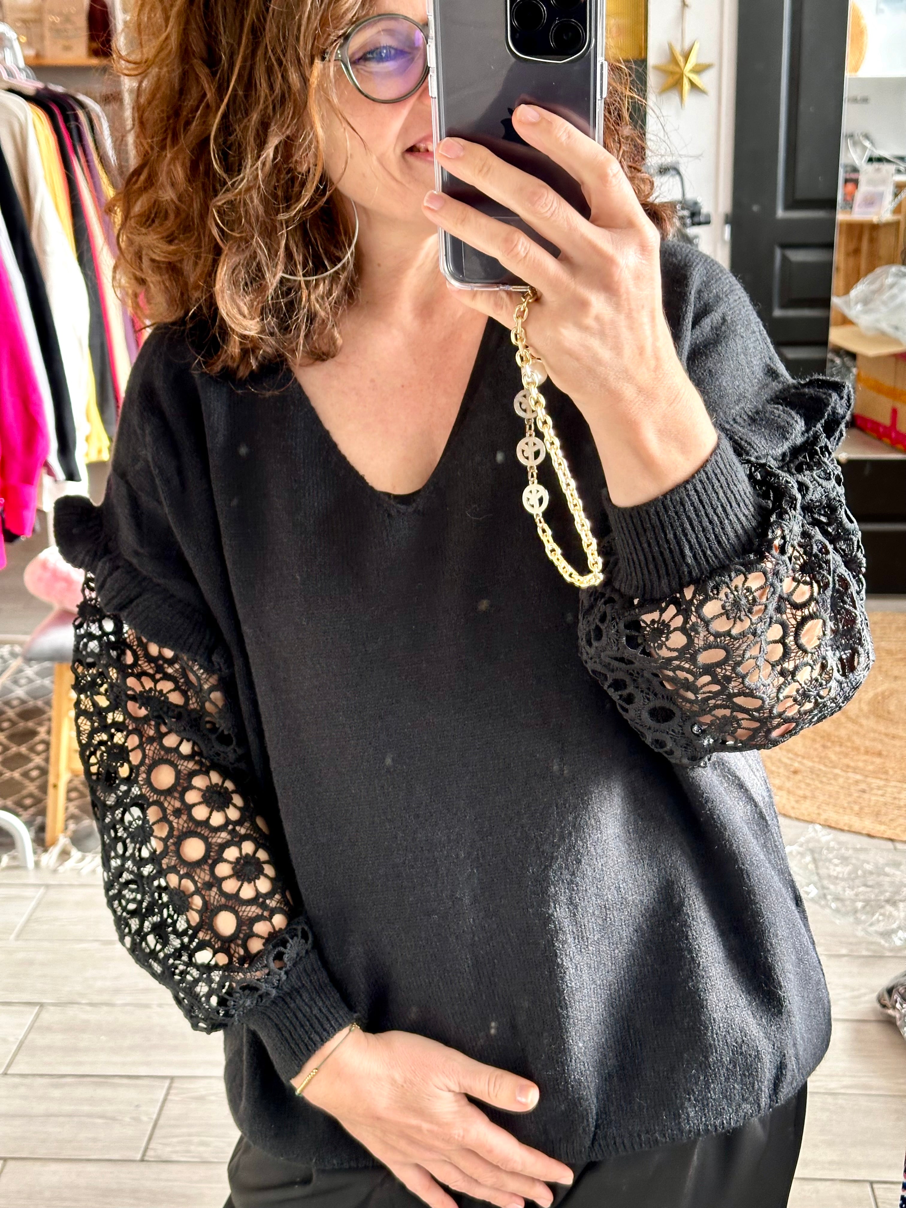 Pull Mila noir avec manches en dentelle élégante, porté avec un col en V, disponible jusqu'à la taille 48.