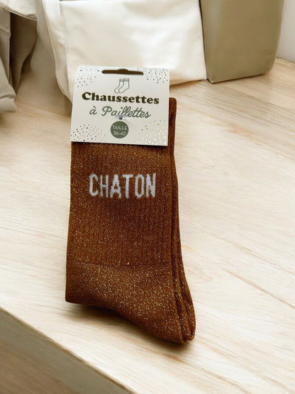 Détail des chaussettes scintillantes avec différents noms en blanc, parfaites pour un look fun et original