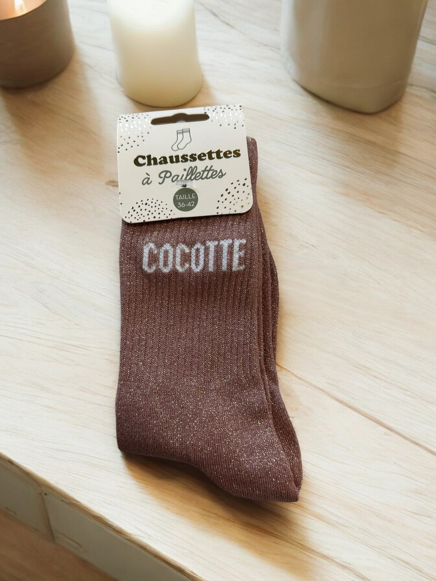 Chaussettes avec inscriptions humoristiques et pailletées, photographiées sur fond blanc doux, idéales pour un style décontracté et pétillant