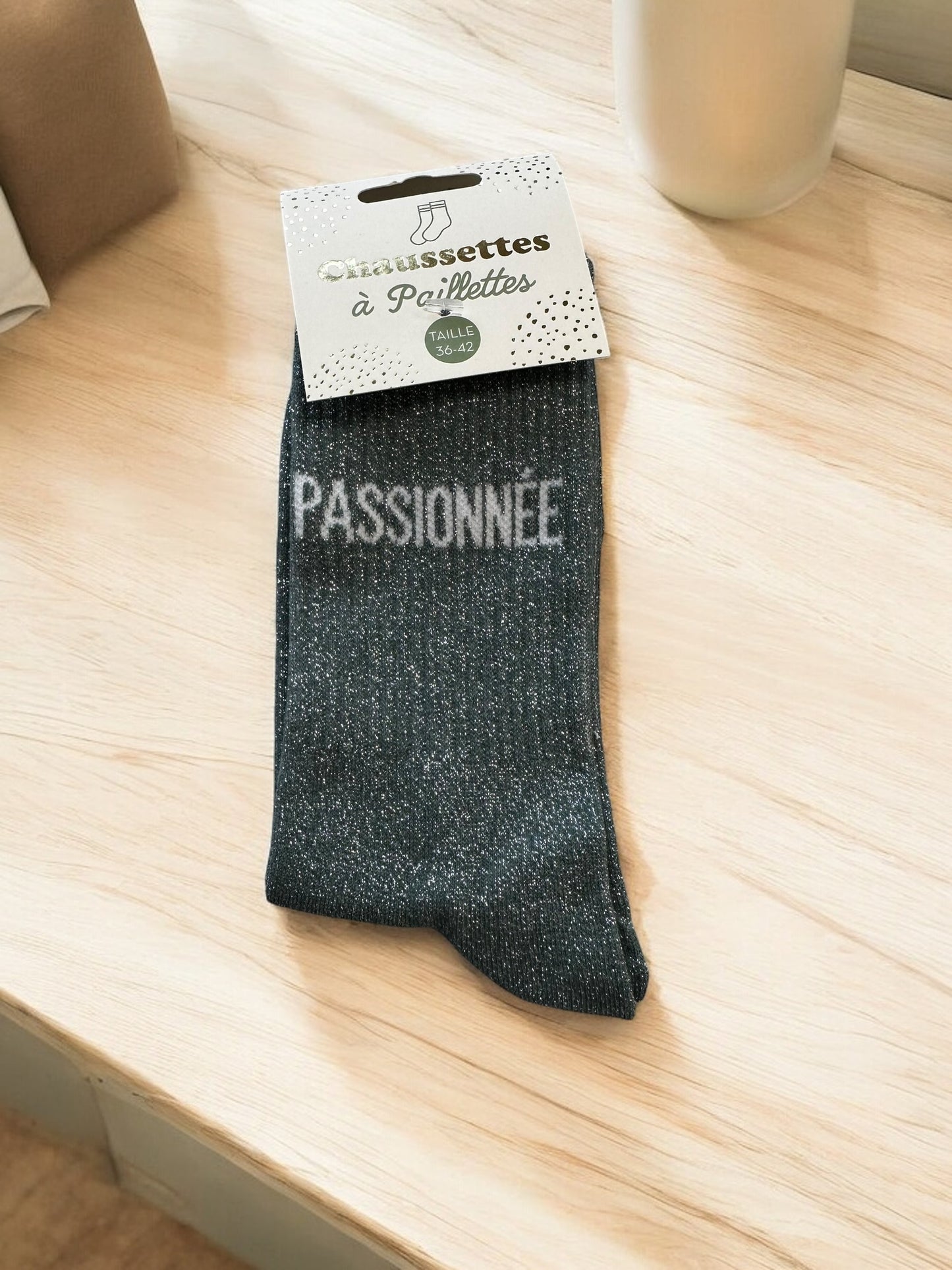 Chaussettes avec inscriptions humoristiques et pailletées, photographiées sur fond blanc doux, idéales pour un style décontracté et pétillant